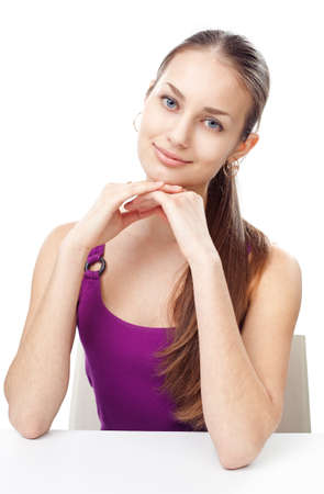 Portrait of pretty young girl sitting at table isolated on white backgroundの写真素材