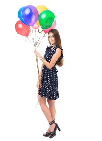 Full length portrait of beautiful smiling young woman in polka dot dress holding colorful balloons isolated on white backgroundの写真素材