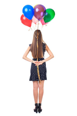 Full length back view of woman in polka dot dress holding colorful balloons behind her back isolated on white backgroundの写真素材