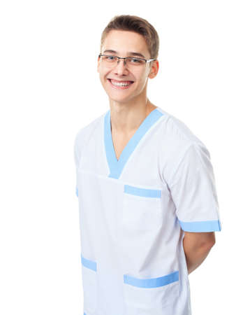 Portrait of happy smiling young doctor in uniform with hands behind his back isolated on white backgroundの写真素材