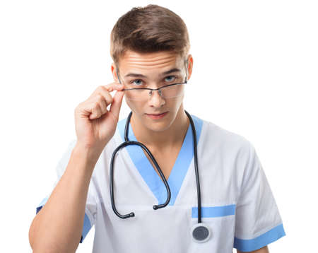 Portrait of young doctor with stethoscope looking over glasses isolated on white backgroundの写真素材