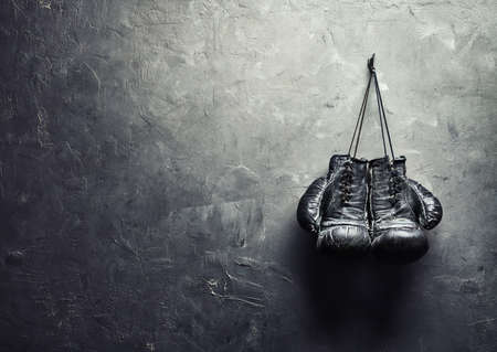 old boxing gloves hang on nail on texture wall with copy space for text  Retirement concept