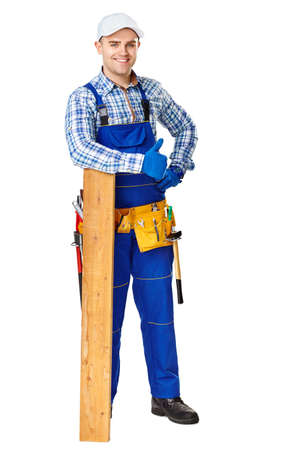 Full length portrait of happy young carpenter leaning on a wooden plank and showing thumbs up gesture isolated on white backgroundの写真素材