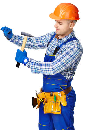 Young working man wearing protective clothes,gloves and helmet with hammer driving a nail in wall isolated on white backgroundの写真素材