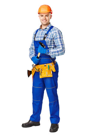 Full length portrait of smiling young male construction worker with hammer,wearing protective clothes,gloves and helmet isolated on white backgroundの写真素材