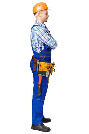 Full length side view portrait of young male construction worker wearing protective clothes, helmet and tool belt isolated on white backgroundの写真素材