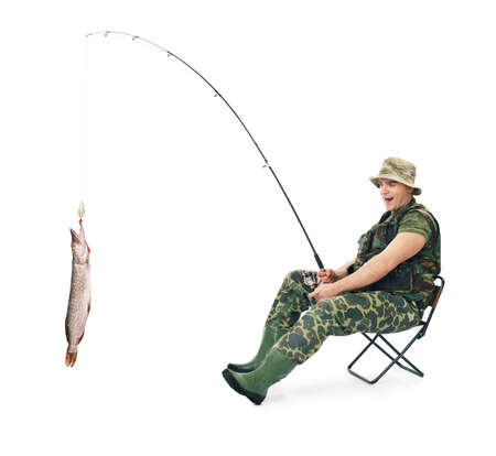 Young happy fisherman in camouflage catching a fish sitting on a chair isolated on white backgroundの写真素材