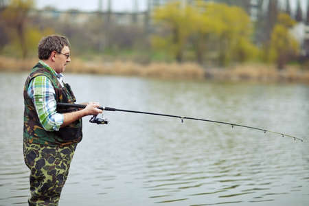 Mature fisherman angling on the riverの写真素材