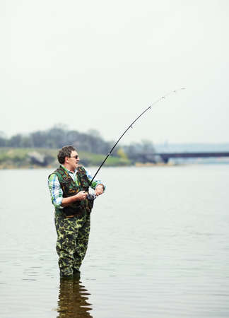 Mature fisherman angling on the riverの写真素材