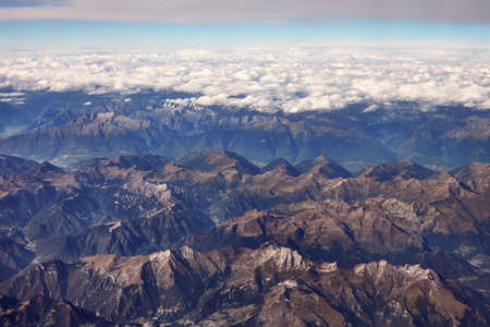 The view from the airplane window at alps mountains and cloudsの写真素材