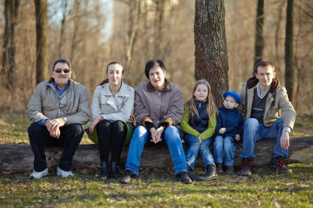 Big happy family portrait sitting on a big log in early spring parkの写真素材