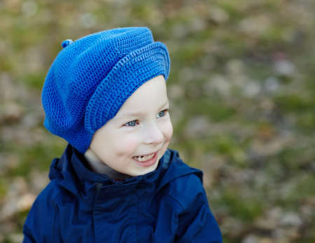 Portrait of cute smiling little boy wearing a blue hat in the autumn parkの写真素材