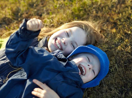 Happy sister and brother having fun on the lawn in autumn park. Happy lifestyle kids