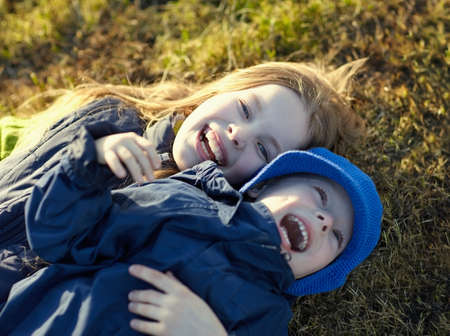 Happy sister and brother having fun on the lawn in autumn park. Happy lifestyle kidsの写真素材
