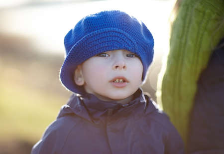 Close-up portrait of cute little boy wearing a blue hat in the autumn parkの写真素材