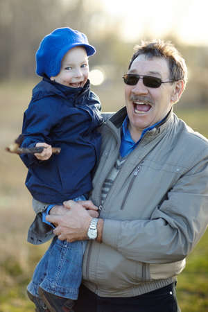 Happy grandfather and grandson having fun in autumn park