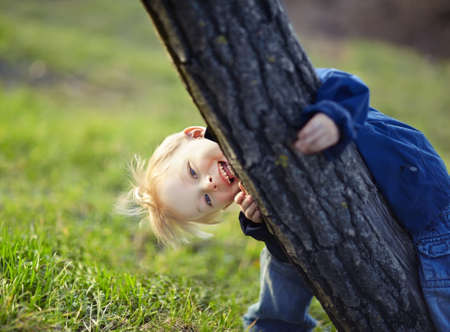 Happy little boy having fun near the tree in the spring parkの写真素材