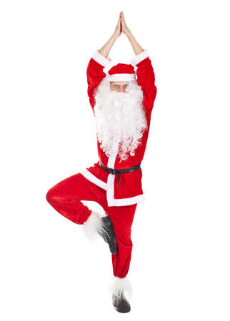 Happy Christmas Santa Claus doing yoga exercise tree-pose isolated on white backgroundの写真素材