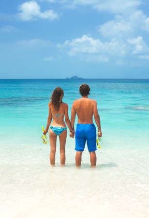 Couple on the beach with snorkel equipment. Young couple snorkeling together in a topical seaの写真素材