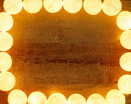 Lights frame on wooden background with copy space. Decorative garland