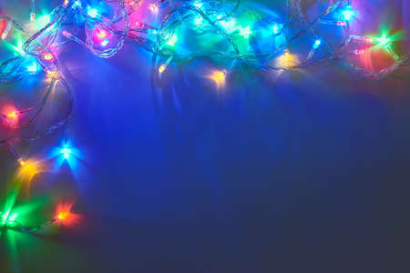 Christmas lights frame on dark blue background with copy space. Decorative garland