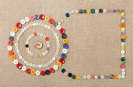 Circles of colorful sewing buttons on fabric texture background with copy spaceの写真素材