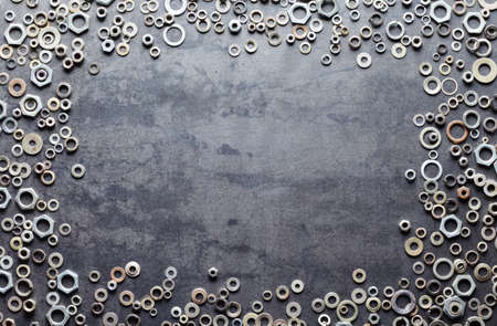 Assorted screw nuts and bolts frame on metal texture backgroundの写真素材