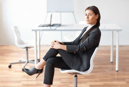 Portrait of young business woman sitting on chair in the office
