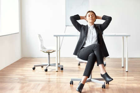 Portrait of young business woman sitting on chair in the officeの写真素材
