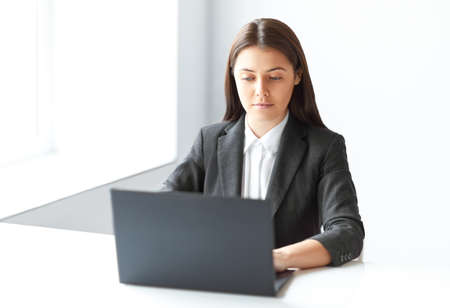 Portrait of young pretty business woman with laptop in the officeの写真素材