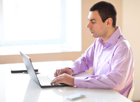 Portrait of young business man with laptop in the officeの写真素材