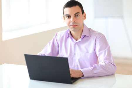 Portrait of young business man with laptop in the officeの写真素材