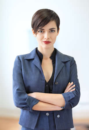 Portrait of young beautiful business woman in the office. Crossed armsの写真素材