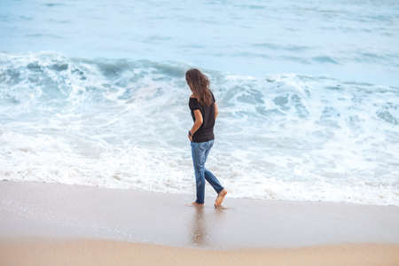 beautiful woman walking along tropical sea in storm
