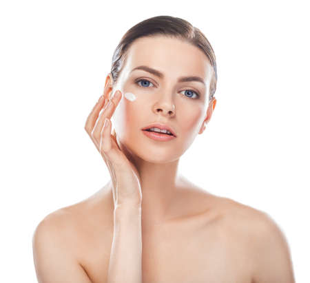 Closeup portrait of beautiful young woman with cosmetic cream on a cheek isolated on white backgroundの写真素材
