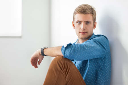 Handsome serious man sitting on the floor in studioの写真素材