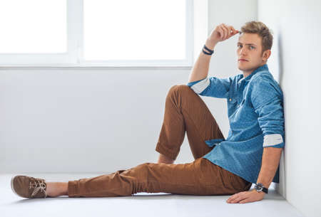 Handsome serious man sitting on the floor in studioの写真素材