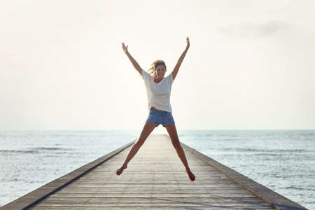 Happy jumping girl on the pier. Freedom conceptの写真素材