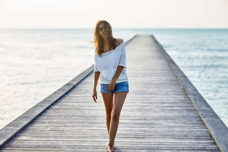 Young beautiful woman walking on the pierの写真素材