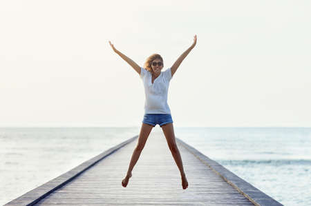 Happy jumping girl on the pier. Freedom conceptの写真素材