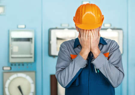 Portrait of stressed despair engineer closed face by two handsの写真素材