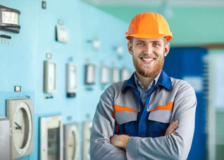 Portrait of young happy engineer at control room. Crossed armsの写真素材