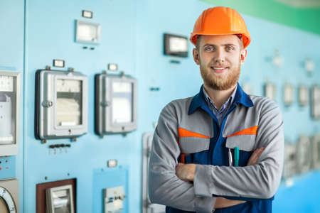 Portrait of young happy engineer at control room. Crossed armsの写真素材