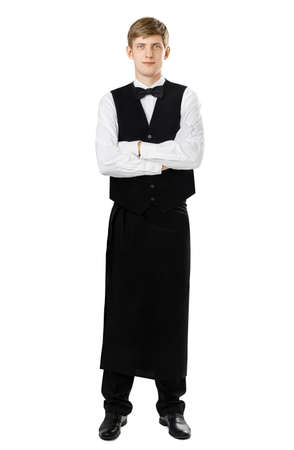 Full length portrait of young handsome waiter standing with crossed arms isolated on white backgroundの写真素材