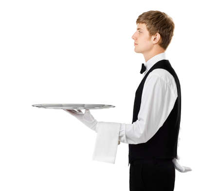 Profile portrait of young handsome waiter holding empty tray with copy space isolated on white backgroundの写真素材