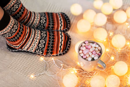 Woman feet in woollen socks and cup of hot chocolate. Christmas holidays concept.の写真素材
