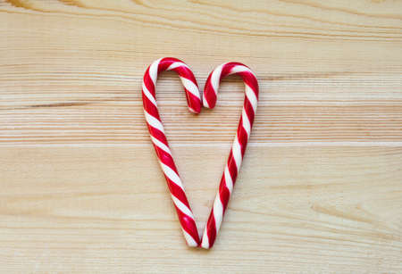 Candy Canes in Heart Shape on wooden background. Christmasの写真素材