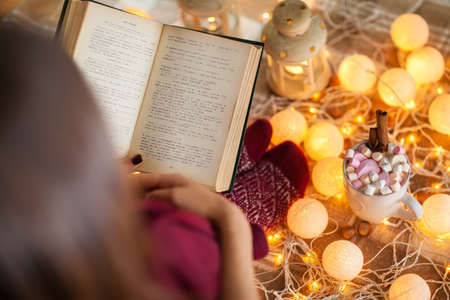 Top view of young woman at home reading book. Winter holiday conceptの写真素材