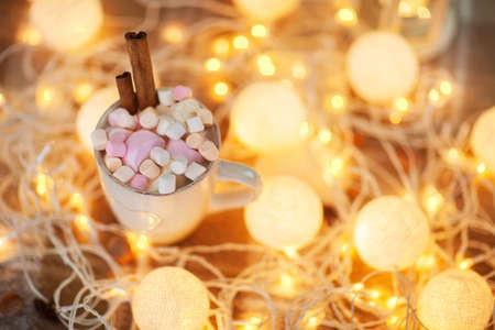 Cup of hot chocolate with multicoloured marshmallows on christmas light backgroundの写真素材