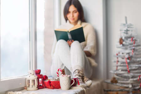 Woman reading book in christmas decorated home. Holiday concept